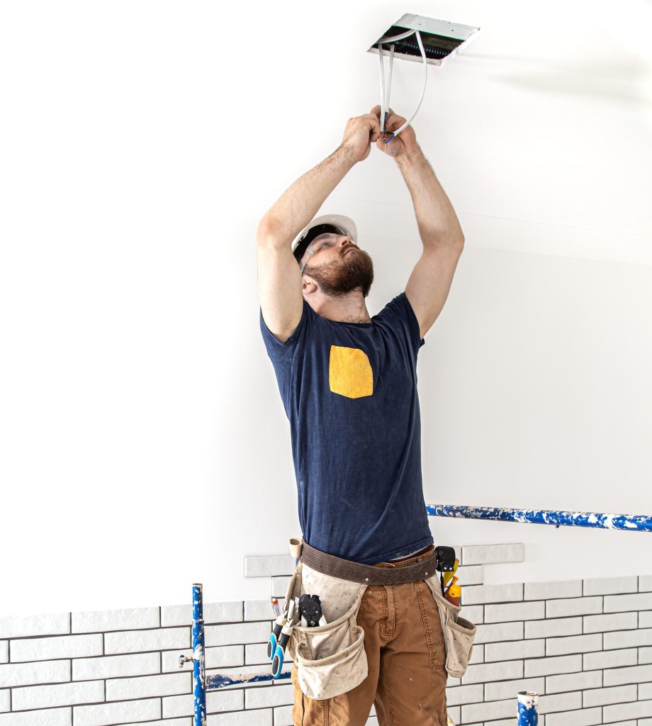 Electrician Builder at work, installation of lamps at height.